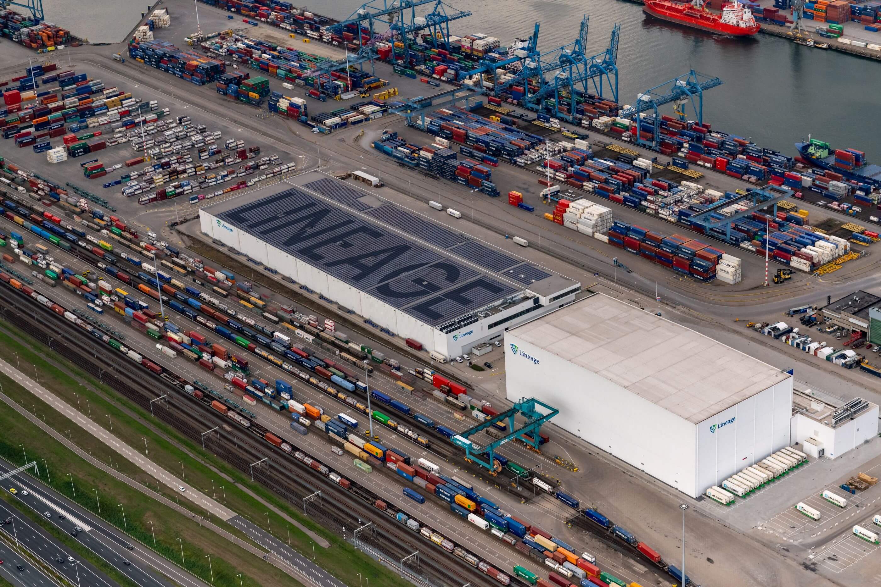 Exterior drone shot of Lineage Cool Port 2 cold storage facility surrounded by refrigerated rail cars in the Port of Rotterdam, NE.