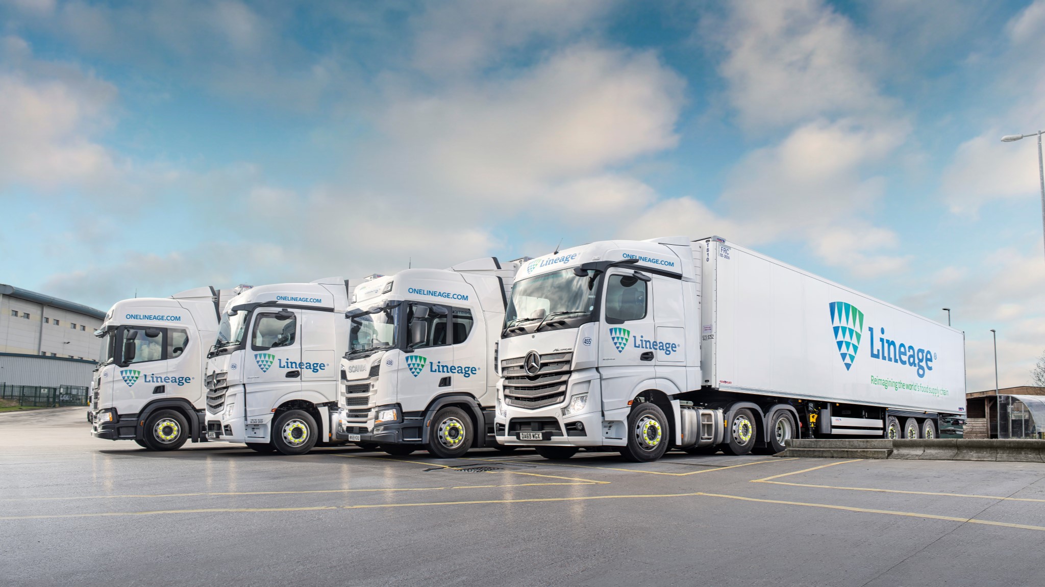 Four Lineage trucks parked in front of a building, showcasing a clear view of the vehicles and the structure behind them