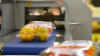 Packed fresh yellow bell peppers on a conveyor belt in a cold chain food processing facility, ready for temperature-controlled logistics.